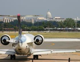 Airplane landing on a runway with Washington, DC skyline, including White House, in background